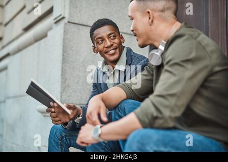 Die Straßen sind voller Geschäfte. Aufnahme von zwei jungen Geschäftsleuten, die vor städtischem Hintergrund ein informelles Treffen abhalten. Stockfoto