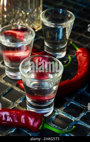 Ein Glas Wodka mit Paprika auf dunklem Hintergrund Stockfoto