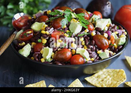 Hausgemachter mexikanischer Salat mit schwarzen Bohnen und Mais oder texanisches Kalksandressing mit Kaviarbohnendip, serviert mit Tortilla-Chips und frischen Zutaten. Stockfoto