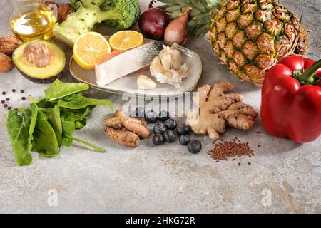 Set aus frischem Gemüse, Fisch, Früchten, Nüssen und Gewürzen für eine entzündungshemmende und antioxidative Ernährung, gesundes Lebensmittelkonzept, hellgrauer Steinrückstand Stockfoto