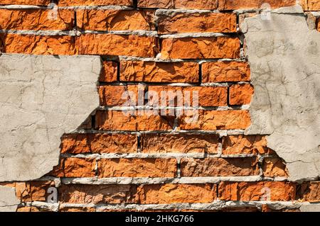 Alte Backsteinmauer mit abgefallener Gips. Hintergrund der Risse Ziegelwand Textur Stockfoto