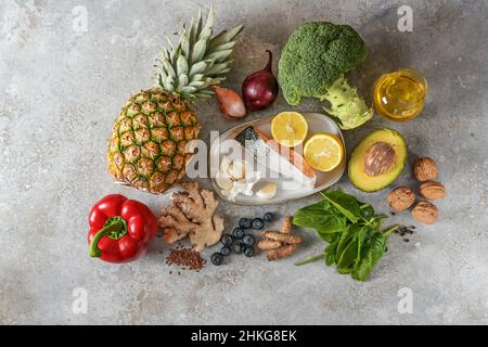 Gesunde Lebensmittel mit entzündungshemmender und antioxidativer Wirkung, Set aus frischem Gemüse, Fisch, Früchten, Nüssen und Gewürzen für ein Diätkonzept auf hellgrauer st Stockfoto