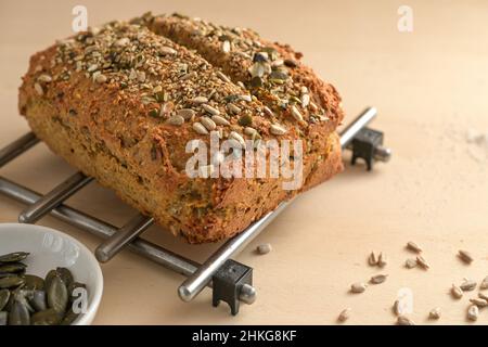 Selbstgebackenes Brot aus Vollkornmehl und Samen auf einem Gitter und auf einem Holztisch, gesundes Esskonzept, Kopierraum, ausgewählter Fokus, enge Tiefe von f Stockfoto