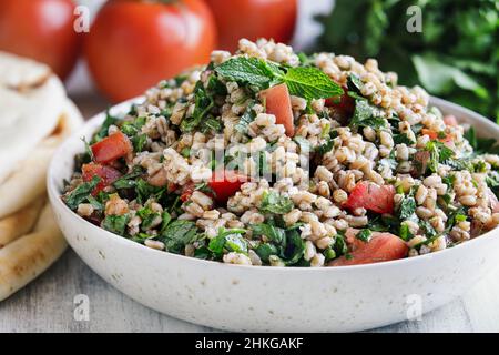 Salat aus Tabbouleh. Traditionelles levantinisches mittelöstliches oder arabisches Gericht für Iftar aus Petersilie, Minze, Bulgur und Tomaten. Serviert mit Pita Fladenbrot. Stockfoto