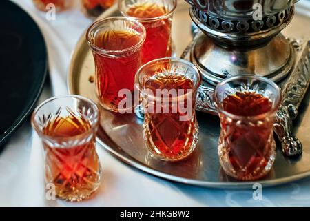 Tee in nationalen türkischen Gläsern auf einem Tablett, neben dem Samowar. Stockfoto
