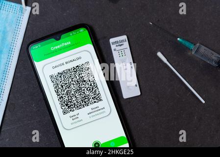Ein positiver Covid-Schnelltest, auch Antigentest oder Lateral-Flow-Test genannt, wird in einer Nahaufnahme auf einem Tisch zusammen mit einem Handy-Showin gesehen Stockfoto