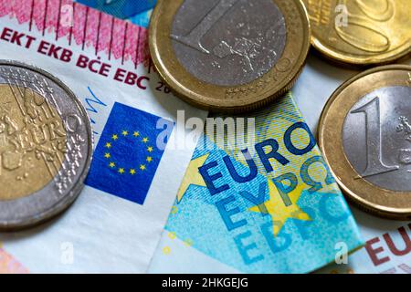 Bargeld der Europäischen Union: Details verschiedener Euro-Banknoten und -Münzen. Nahaufnahme mit dem Wort „Euro“, der EU-Flagge, mit 50 Cent-, 1- und 2-Euro-Münzen Stockfoto