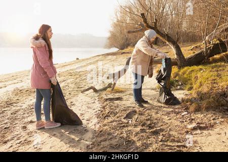 Zwei Freiwillige säubern den Müll an einem Flussufer Stockfoto