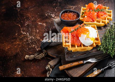 Waffle Sandwich mit Frischkäse, geräuchertem Lachs, Ei und rotem Kaviar. Dunkler Hintergrund. Draufsicht. Speicherplatz kopieren Stockfoto