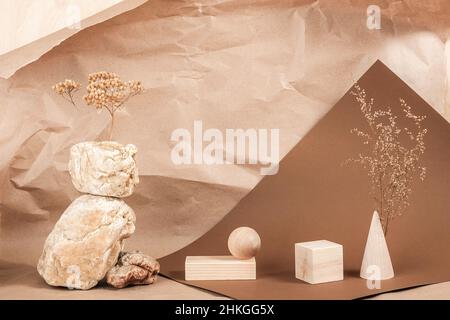 Kreative Podium für Kosmetik oder Sie Merchandise, Produkte. Grundriss aus geometrischen Holzformen, Steinen und getrockneten Blumen auf braunem beigefarbenem Papier Stockfoto