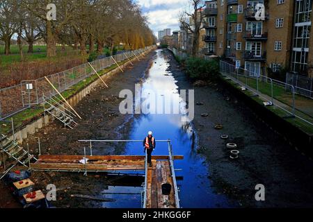 Ein Bauarbeiter baut eine Plattform auf dem entwässerten Hertford Union Canal in der Nähe des Victoria Parks im Osten Londons. Der Kanal, der den Regent's Canal mit der Lee Navigation verbindet, ist fast 200 Jahre alt und ein Abschnitt wurde drei Monate lang geschlossen und abgepumpt, damit an seinen Wänden wesentliche Reparaturarbeiten durchgeführt werden können. Bilddatum: Freitag, 4. Februar 2022. Stockfoto