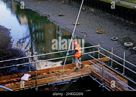 Ein Bauarbeiter baut eine Plattform auf dem entwässerten Hertford Union Canal in der Nähe des Victoria Parks im Osten Londons. Der Kanal, der den Regent's Canal mit der Lee Navigation verbindet, ist fast 200 Jahre alt und ein Abschnitt wurde drei Monate lang geschlossen und abgepumpt, damit an seinen Wänden wesentliche Reparaturarbeiten durchgeführt werden können. Bilddatum: Freitag, 4. Februar 2022. Stockfoto