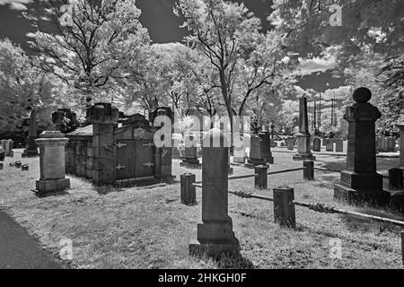 Ein sehr alter Friedhof in einem Hof der englischen Reform Church aus dem Jahr 1776. Dieses infrarote, abstrakte, schwarz-weiße Foto ist ein Grusel und ein guter Look für Halloween. Stockfoto