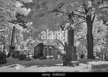 Ein sehr alter Friedhof in einem Hof der englischen Reform Church aus dem Jahr 1776. Dieses infrarote, abstrakte, schwarz-weiße Foto ist ein Grusel und ein guter Look für Halloween. Stockfoto