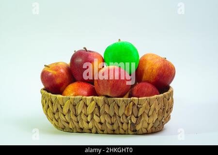Ein grüner Apfel unter vielen roten Äpfeln in einem Korb Stockfoto