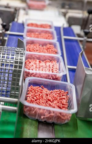 Formen aus Hackfleisch zum Verpacken. Linie für die Herstellung von Halbfabrikaten.Fleischverarbeitung in der Lebensmittelindustrie.Verpackung von Fleischscheiben i Stockfoto