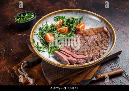 Diner mit gegrilltem Rinderfleisch-Steaks und Gemüsesalat. Dunkler Hintergrund. Draufsicht Stockfoto