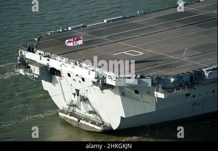 Das Fähnrich der Royal Navy am Heck des Flugzeugträgers der Royal Navy, HMS Prince of Wales, kommt nach den Übungen vom Spinnaker Tower aus gesehen zurück in den Hafen von Portsmouth. Der Flugzeugträger dient derzeit als NATO-Kommandoschiff für das nächste Jahr, nachdem die Royal Navy die schnelle Reaktion der NATO maritime Task Force übernahm, die gebildet wurde, um größere Zwischenfälle auf der ganzen Welt anzugehen. Bilddatum: Freitag, 4. Februar 2022. Stockfoto