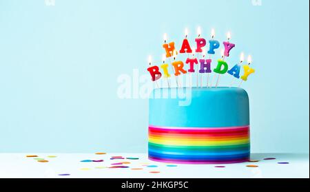 Bunte Regenbogen Geburtstagstorte mit Regenbogen Band und Regenbogen Geburtstagskerzen Stockfoto