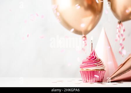 Geburtstagsfeier mit rosa Geburtstagskuchen, Partyhüten und roségoldfarbenen Ballons Stockfoto