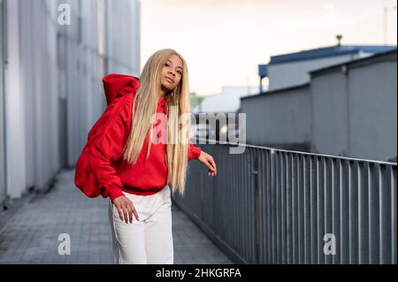 Fröhliche afroamerikanische Frau mit langen blonden Haaren, die Sportkleidung trägt und Kopfhörer trägt Stockfoto