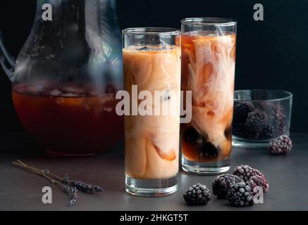 Gläser Eistee, gewürzt mit Brombeeren und Creme: Eistee Earl Grey, gesüßt mit Honig und garniert mit gefrorenen Brombeeren Stockfoto