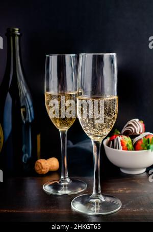 Durchgehendes Glas Champagner in Flötengläsern: Sekt in Sektgläsern mit schokoladenüberzogenen Erdbeeren Stockfoto