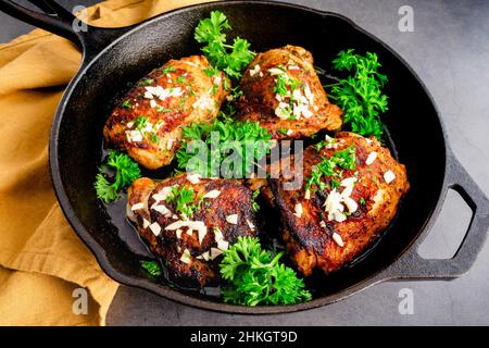 Gebratenes Olivenöl Chicken Thighs Mediterranean Style: Gewürzte Chicken Thighs, die in einer gusseisernen Pfanne gebraten wurden Stockfoto