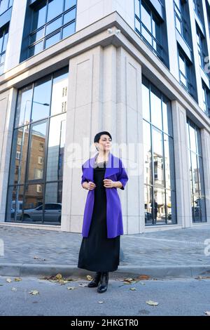 Eine elegante Frau in stilvollem Outfit posiert auf einer Stadtstraße. Stockfoto