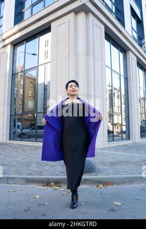 Eine elegante Frau in stilvollem Outfit posiert auf einer Stadtstraße. Stockfoto
