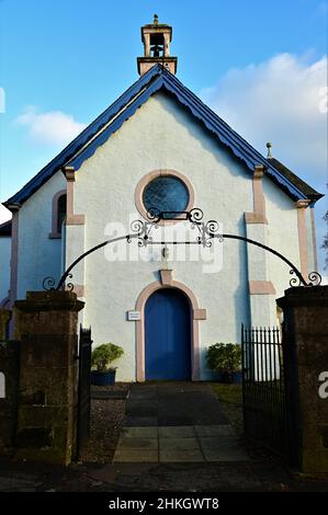 Außenansicht des kleinen ländlichen Kirchengebäudes im Dorf Drymen und des alten Friedhofs, der ihn umgibt. Stockfoto