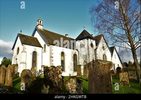 Außenansicht des kleinen ländlichen Kirchengebäudes im Dorf Drymen und des alten Friedhofs, der ihn umgibt. Stockfoto