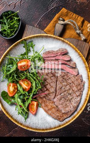 Diner mit gegrilltem Rinderfleisch-Steaks und Gemüsesalat. Dunkler Hintergrund. Draufsicht Stockfoto