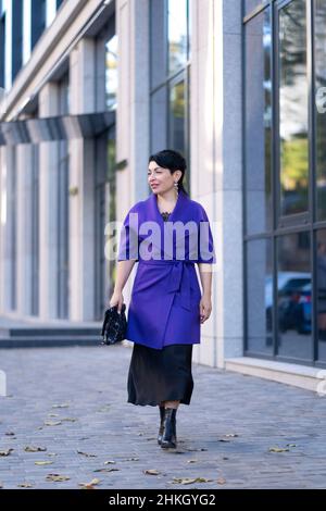 Eine elegante Frau in stilvollem Outfit posiert auf einer Stadtstraße. Stockfoto