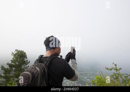 Tourist mit Rucksack macht Fotos mit Smartphone in den Bergen Stockfoto