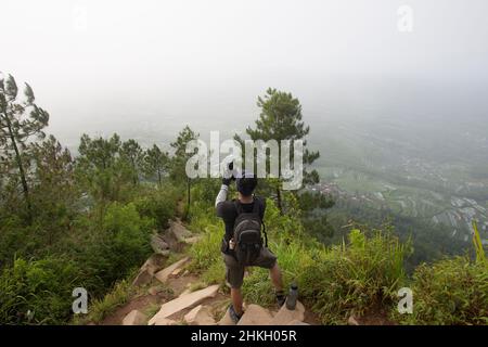 Tourist mit Rucksack macht Fotos mit Smartphone in den Bergen Stockfoto