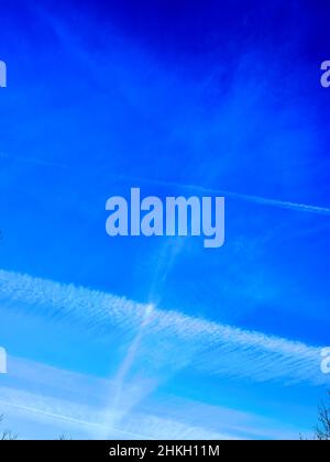 Dampfspuren und Wolken gegen einen strahlend blauen Januarhimmel Stockfoto