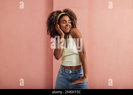 Junge lächelnde Frau, die Musik genießt. Glückliche Frau, die Kopfhörer trägt und wegschaut. Stockfoto