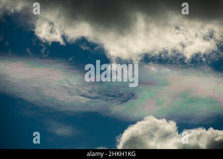 Verschiedene Farben in Wolke am blauen Himmel zwischen weißen Wolken Blaupinken und Grünsonnen Reflexion in Wolken am blauen Himmel atmosphärische Wirkung oben Stockfoto