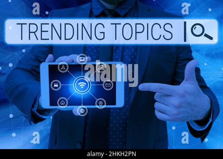 Hand schreiben Zeichen Trending Themen. Wort zum Thema geschrieben, dass Erfahrungen Anstieg der Popularität in den sozialen Medien Mann hält Bildschirm des Mobiltelefons Stockfoto
