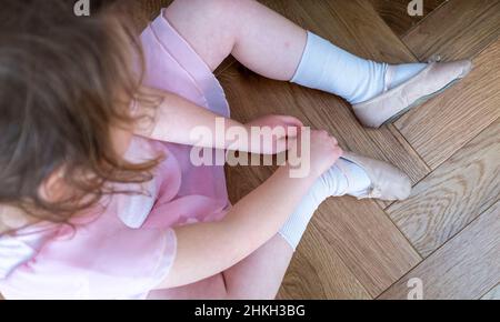 Freche junge 5-jährige Mädchen setzen auf ihre Ballettschuhe bereit für einen Tanzkurs Großbritannien Stockfoto