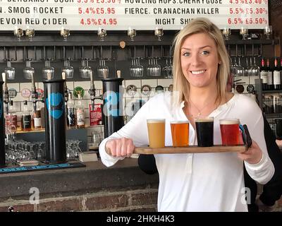 Hübsches blondes Mädchen, das einen Flug von Ale hält Stockfoto