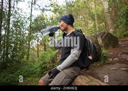 Wandermann, der sich entspannt und Wasser aus der Flasche auf dem Rücken des Berges trinkt Stockfoto