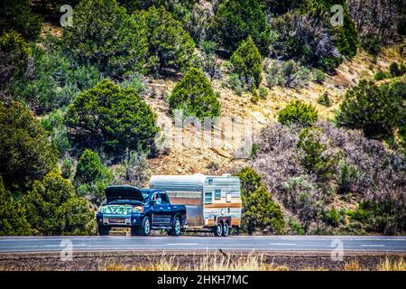 Brokekn unten LKW neben der Straße mit Retro-Wohnmobil und Tuch über Stoßstange und Holztreppen vorne so kurze Person unter der Haube arbeiten kann. Stockfoto