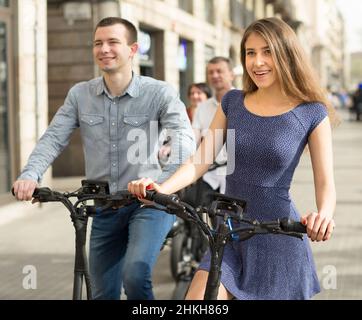 Freunde von Touristen verschiedener Generationen genießen eine Fahrt mit Elektrorollern Stockfoto