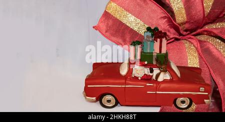 Weihnachtsbanner mit Spielzeug-weihnachtsmann in einem Retro-Auto mit einem Rentier und einem Stapel von Geschenken auf einem hellen Hintergrund mit einem Weihnachtsband - Raum Stockfoto