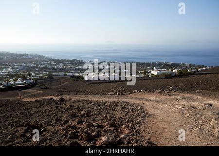 Blick über playa blanca vom Pfad auf den erloschenen roten Montana roja Vulkan in der Nähe von playa blanca Lanzarote Kanarische Inseln Spanien Stockfoto
