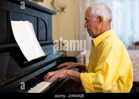 Mann, der im Wohnzimmer seines Heims Klavier spielt, nachdem er sich von der Arbeit verabschiedet hat Stockfoto