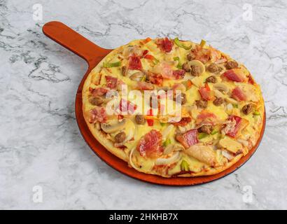 Spezielle Bacon Pizza Belag mit Pilz, geschmolzenem Käse, Tomaten und Fleisch auf Holzbrett und Marmor Hintergrund Stockfoto