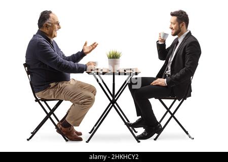Ein Geschäftsmann und ein reifer Mann sitzen an einem Kaffeetisch und trinken isoliert auf weißem Hintergrund Kaffee Stockfoto